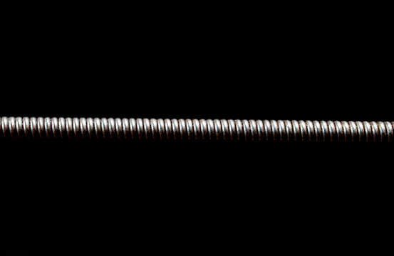 Extreme macro shot of a guitar string isolated on black (shallow DOF, selective focus)