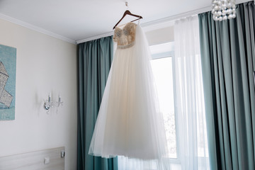 Fototapeta na wymiar Wedding dress hanging on a hanger on the window