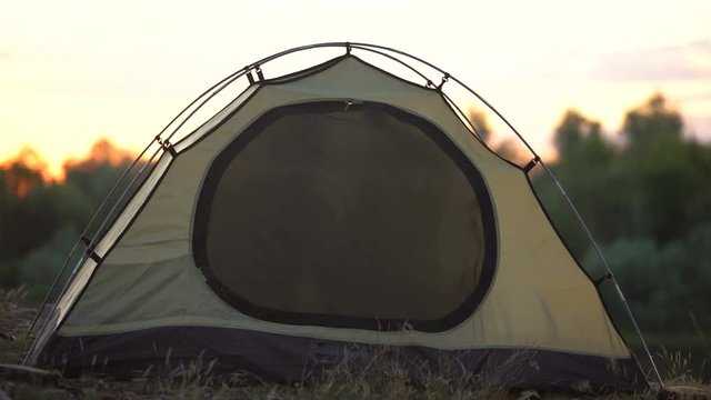 Joyful couple zipping dome tent and winking, preparing to sleep in wild, camp