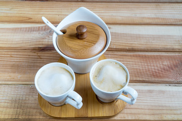 coffee creamers. two cups of coffee on a wooden table.