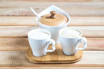 coffee creamers. two cups of coffee on a wooden table.