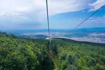 Cable cars going up in to the mountain, green hills