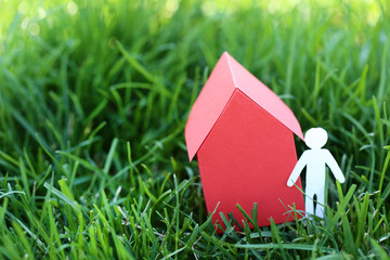 Red paper house with man on green grass