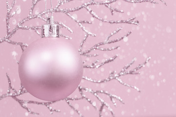 Shiny branch with pink Christmas bauble monochrome with snow , new year background, copy space
