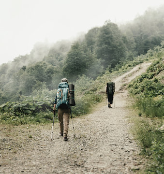 Two hikers walking on the path in mountains.