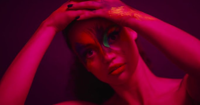 close up colorful portrait beautiful woman wearing fluorescent face paint exotic multicolored body art with flashing ultraviolet light extreme makeup concept