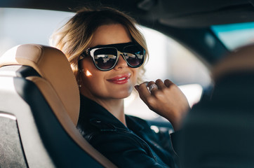 Portrait of smiling blonde r behind wheel in car.