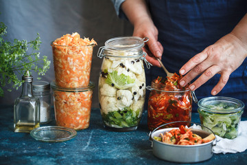 Canning fermented food in jars prep hand  sauerkrauft kimchi broccoli marinated  - obrazy, fototapety, plakaty