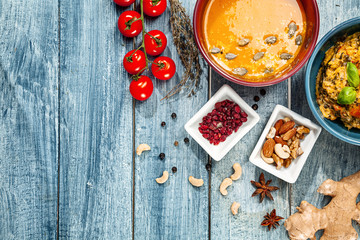 Vegan or vegetarian restaurant dishes top view on blue background. Pumpkin cream soup and rice with herbs and spices. Copy space for text, logo or brand. Healthy food.