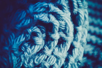 Knit woolen textile texture rolled up backdrop, macro. Grey and Blue color palette clothes with rough rows.