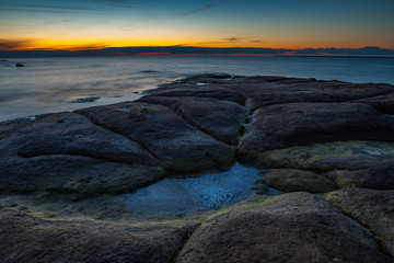 Mystic flat rock laying in the sea. Nightscape after sunset.