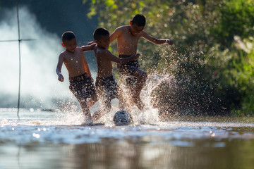Boys kicking football on the river