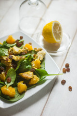 healthy salad with oranges, basil, raisins and honey dressing on white rustic background