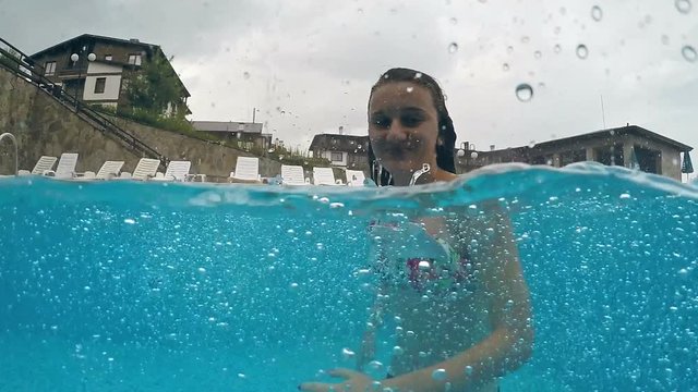 Happy teen in swimming pool smiling to camera at rain raining