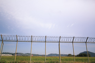 Fototapeta premium Metal fence wire, War and sky in the background in Phuket Thailand