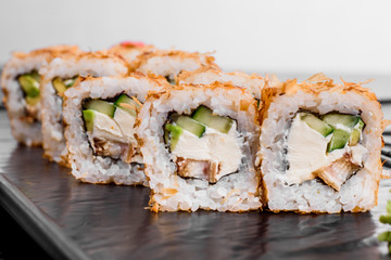 Maki Sushi set on dark pattern background. Sushi Set nigiri, rolls and sashimi served in black square plate