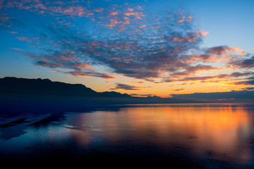 Naklejka na ściany i meble Beautiful colorful sunset in the autumn above the French Alps and Lake Geneva where the colors and clouds reflect beautifully.