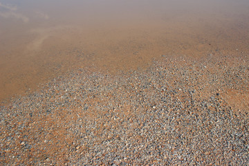 Muddy puddle on beige brown dirt road abstract horizontal