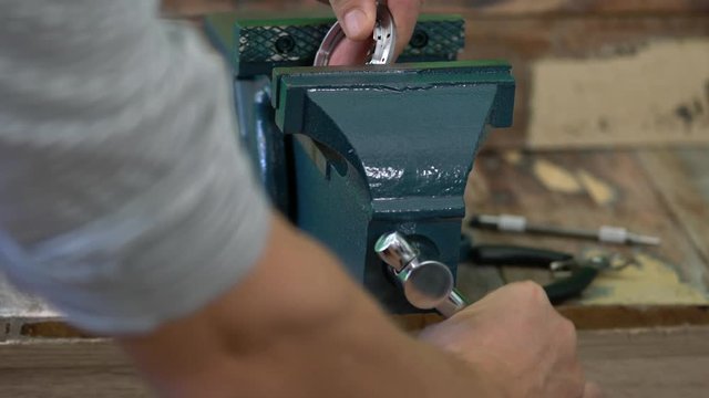 Person spannt Teil in einen Schraubstock ein und dreht dabei am Spannhebel