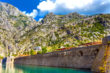Large historical medieval stone wall in front of a moat with green water on the backdrop of the...