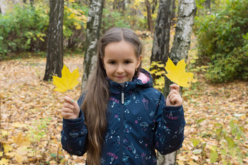 Autumn portrait of beautiful little girl with two leaves