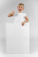 little blond boy holds a blank sign in his hands and points with his thumb upwards