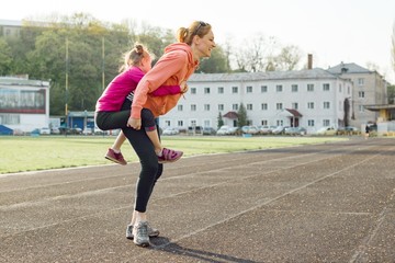Fototapeta premium Sports cheerful family, healthy lifestyle, spring portrait of mother and little daughter having fun and running at the stadium