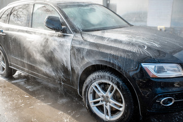 Close-up of a car under the water jet during the washing process on a self service car wash