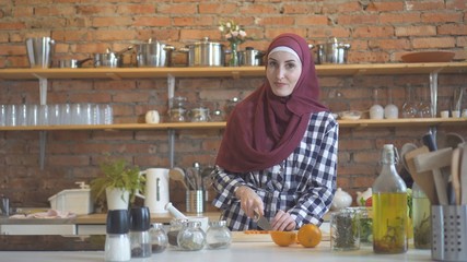 Young muslim woman in kitchen cuts vegetables to cook food