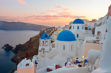 Fototapeta premium townscape Oia, tradycyjna grecka wioska Santorini, z niebieskimi kopułami kościołów o zachodzie słońca, Grecja