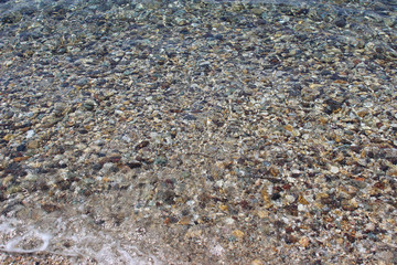 Water sea ocean sand pebbles beach swash wave waterline shallow surface texture clear summer nobody abstract background