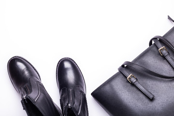Woman accessory. Black stylish boots, black luxury leather bag on white background. Top view background. Flat lay. Copy space.