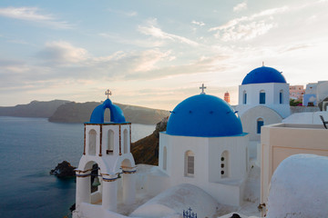 traditional white greek village Oia of Santorini, with blue domes of churches in sunset light, Greece