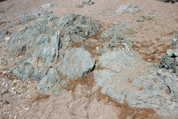 Rocks boulders on beach shore sand grey gray sedimentary detail abstract