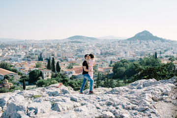 couple have a date on the peak of the hill with panorama view on the city kissing each other