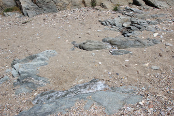 Rocks boulders on beach shore sand grey gray sedimentary detail abstract