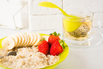Closeup view of oatmeal porridge with fruits and tea