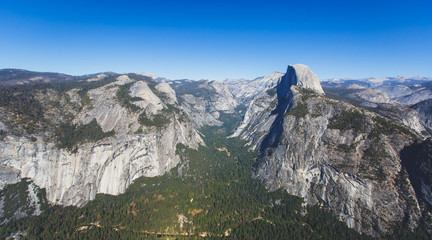 Fototapeta premium Panoramic summer view of Yosemite valley with Half Dome mountain, Tenaya Canyon, Liberty Cap, Vernal Fall and Nevada Fall, seen from Glacier point overlook, Yosemite National Park, California