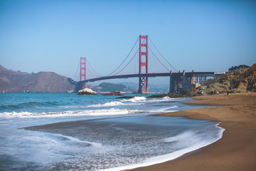 Classic panoramic view of famous Golden Gate Bridge seen from Baker Beach in beautiful summer sunny day with blue sky, San Francisco, California, USA