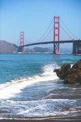 Fototapeta na wymiar Classic panoramic view of famous Golden Gate Bridge seen from Baker Beach in beautiful summer sunny day with blue sky, San Francisco, California, USA