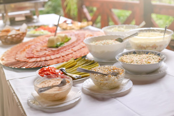 Different types of delicious salads and slices of pork dried meat on large plate. Wedding day food table