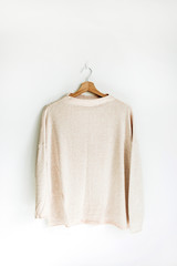 Pastel female pullover on hanger at white wall. Woman fashion clothes concept.