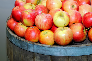 Red fresh apples in a pile on a round wooden barrel