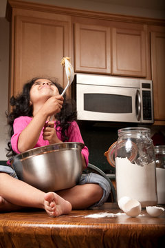 Young girl sitting on counter top with mixing bowl