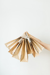 Black Friday sales discount concept. Female hands holding craft paper bags on white background.