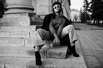 African american fashion girl in coat and newsboy cap, sunglasses posed at street.