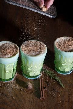 Person grating nutmeg on drinks