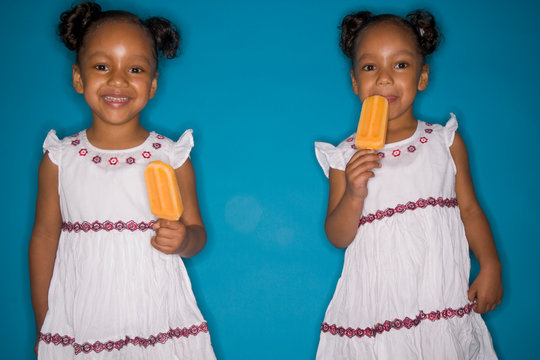 Twin girls eating popsicles