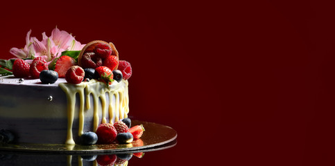 Delicious raspberry cake with fresh strawberries raspberries blueberry waffle and fresh flowers on dark red