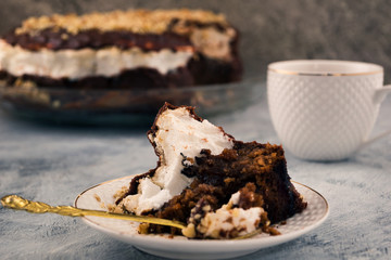 Half-eaten cake on a plate. The remains of the delicious dessert. White porcelain. Light background.